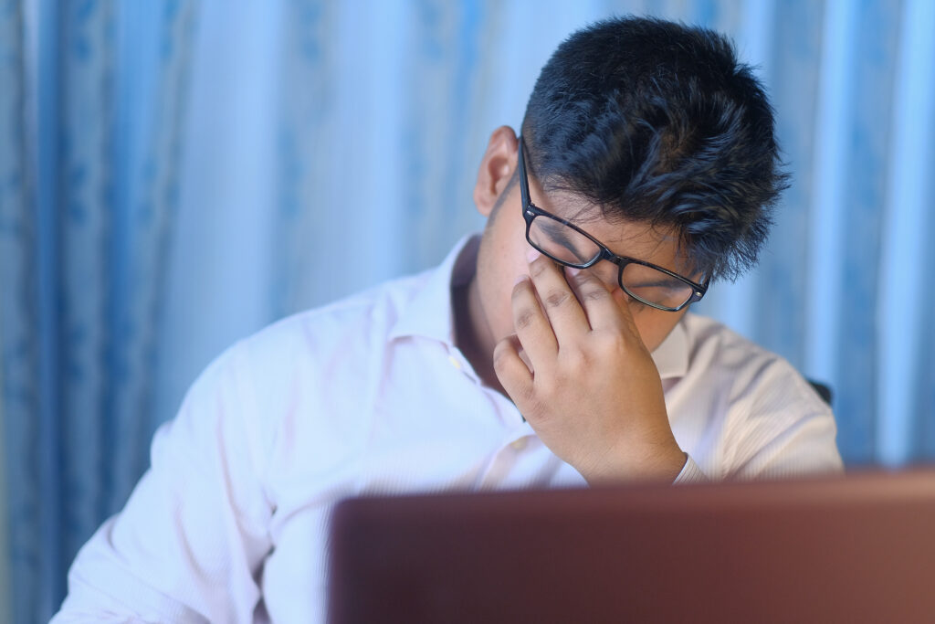A Young Man Who is Feeling Stressed is Diligently Working on His Laptop While at Home child stressed while checking results