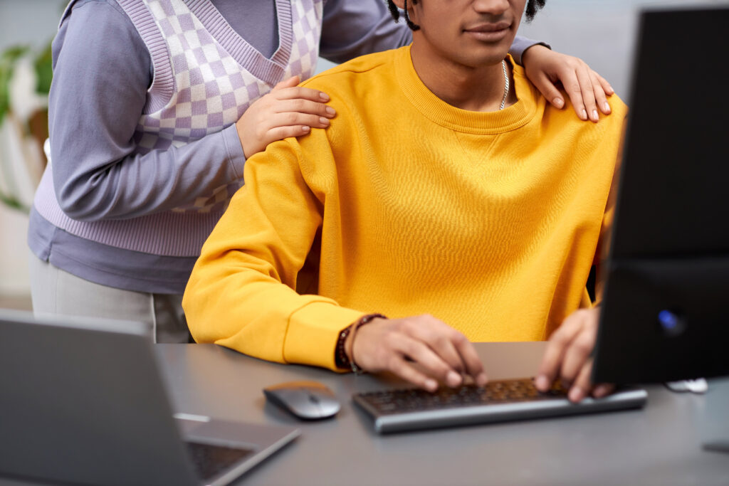 Two young people reviewing code together parent standing while child checks result