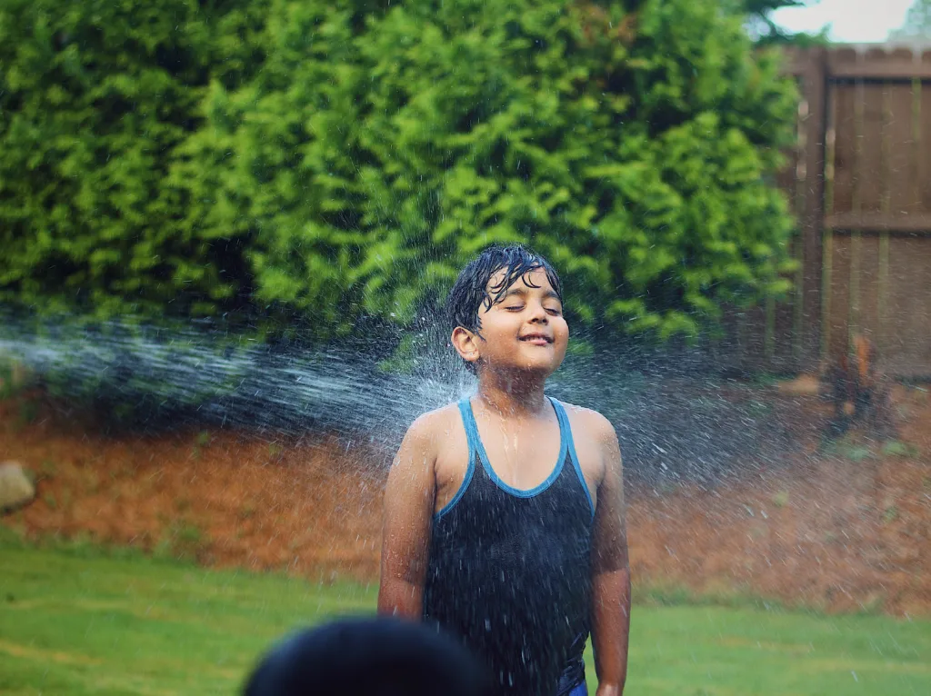 child trying to cool himself from a hose