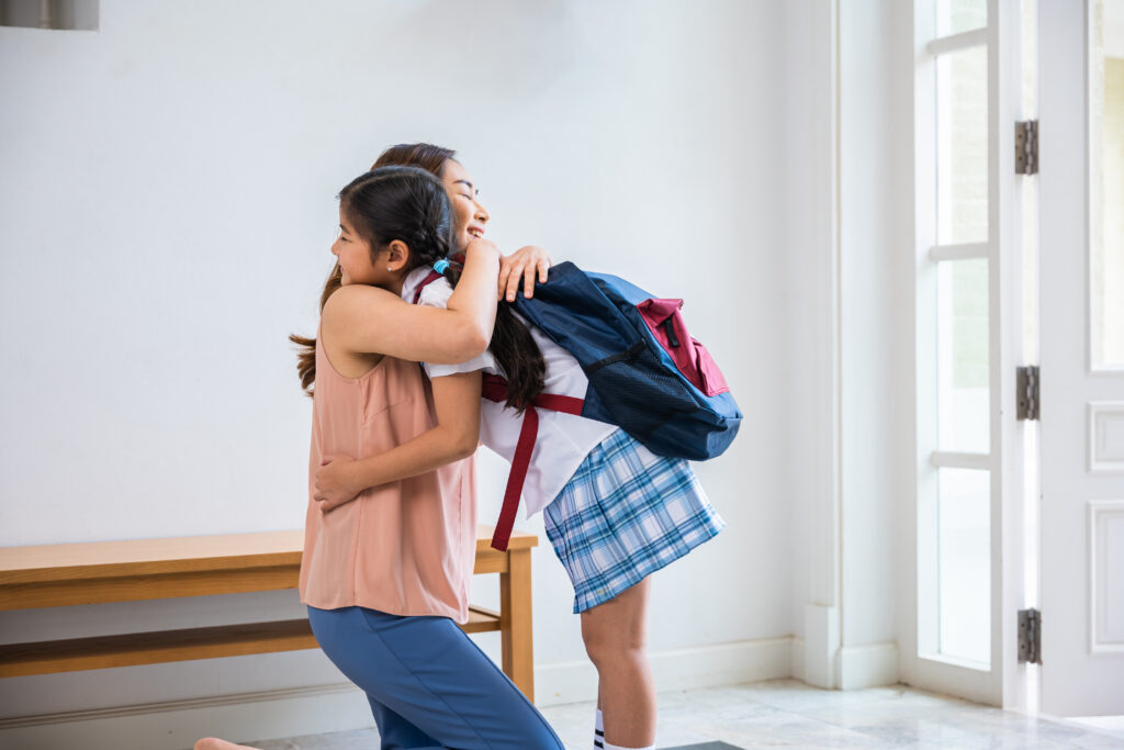 Loving mother and schoolgirl with backpack before first day