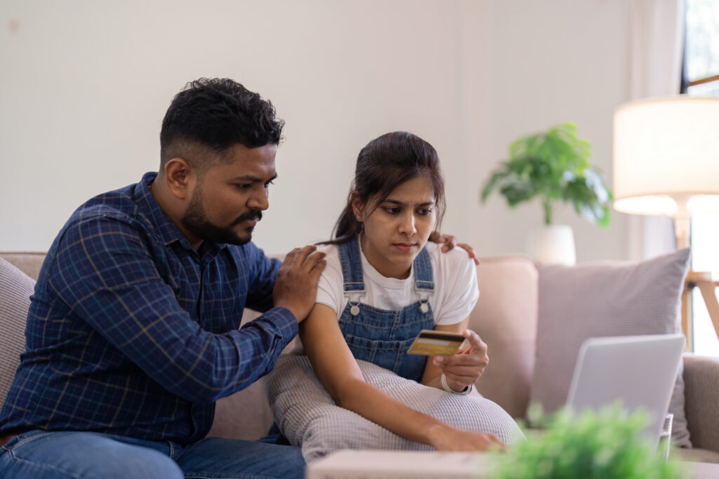 Young indian couple stress using laptop and credit card for shopping online internet payment buying from internet and sitting at home